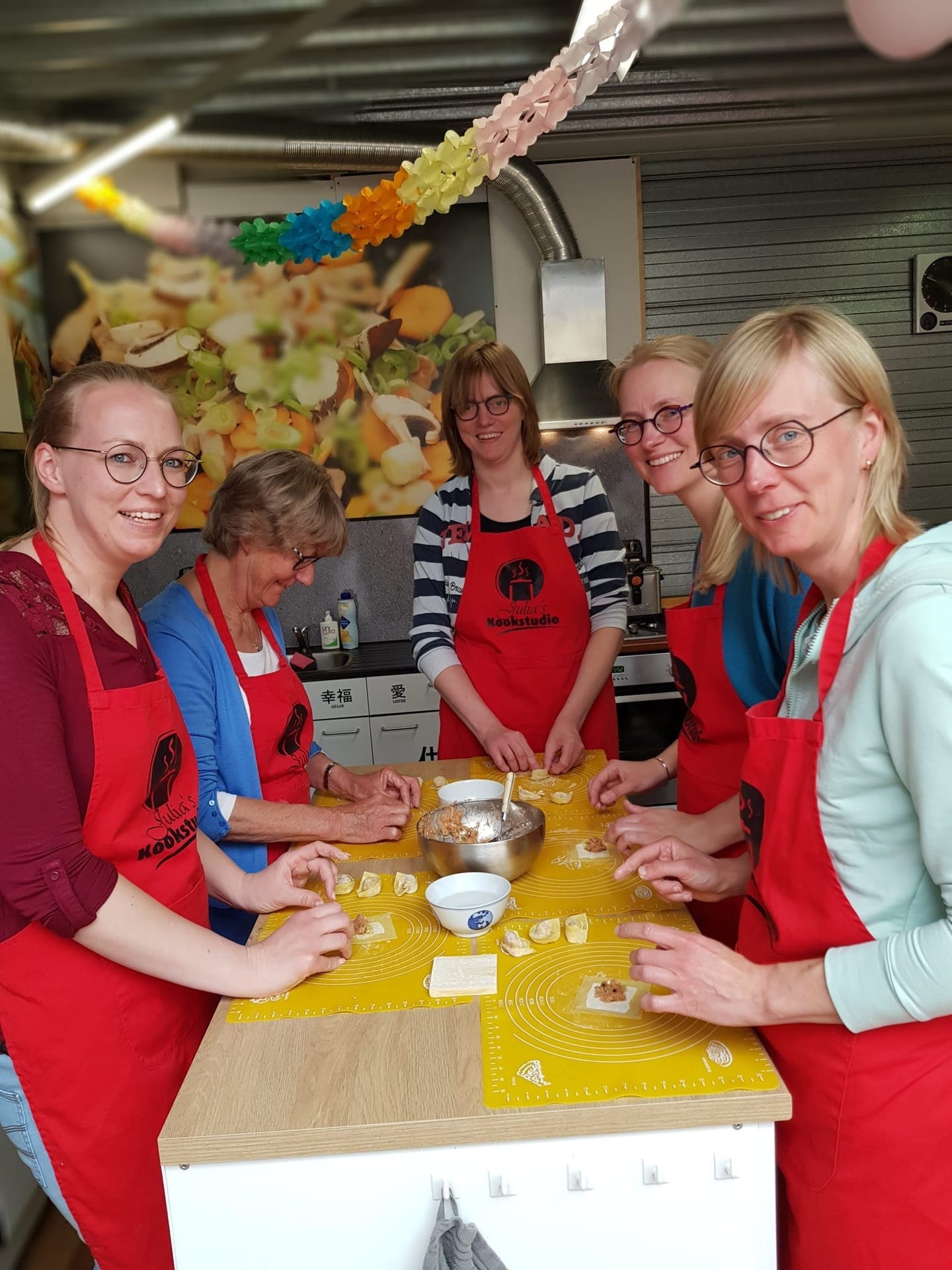 Vijf vriendinnen die dumplings vouwen aan de werktafel